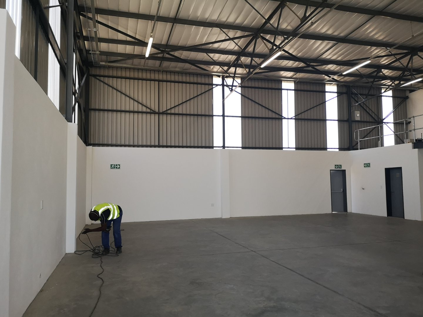 Currie Group Warehouse Interior Spacious warehouse interior with high ceilings, white walls, and a worker inspecting the floor, showcasing modern industrial facilities.