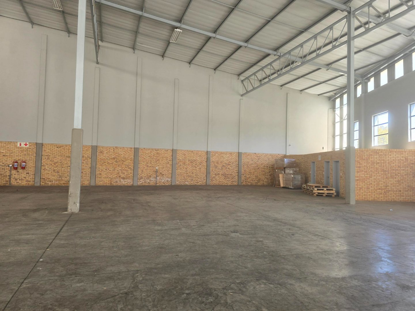 Large, empty warehouse space with high ceilings, brick walls, and concrete flooring in Linbro Park, ideal for storage or industrial use.