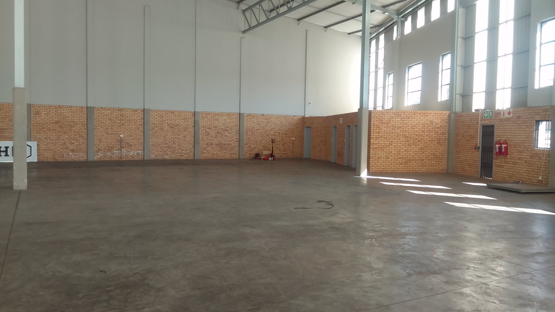 Large, empty warehouse with high ceilings and brick walls in Linbro Park, suitable for storage or industrial use.