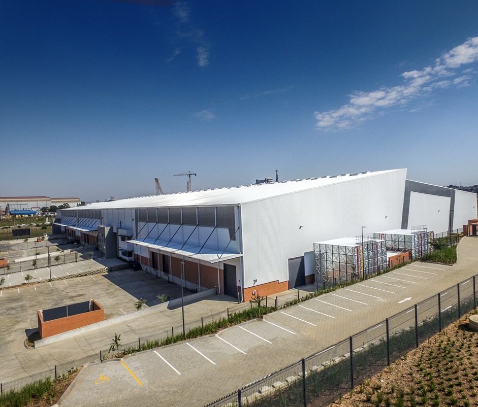 Contemporary office and warehouse building with parking lot and clear blue sky, representing industrial infrastructure since 1887.