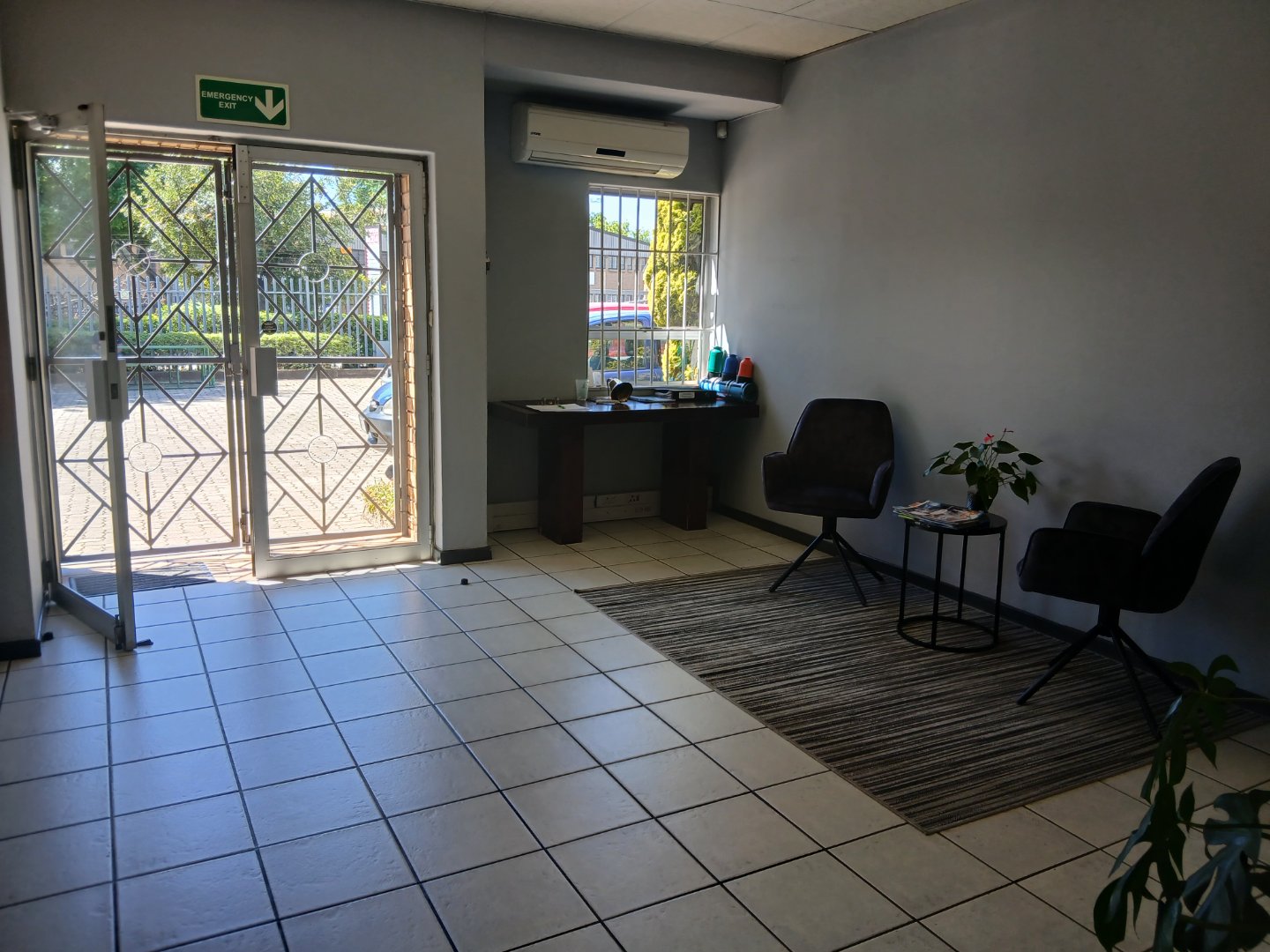 Modern office entrance with glass door, seating area, and indoor plants, showcasing professional workspace environment at Currie Group.