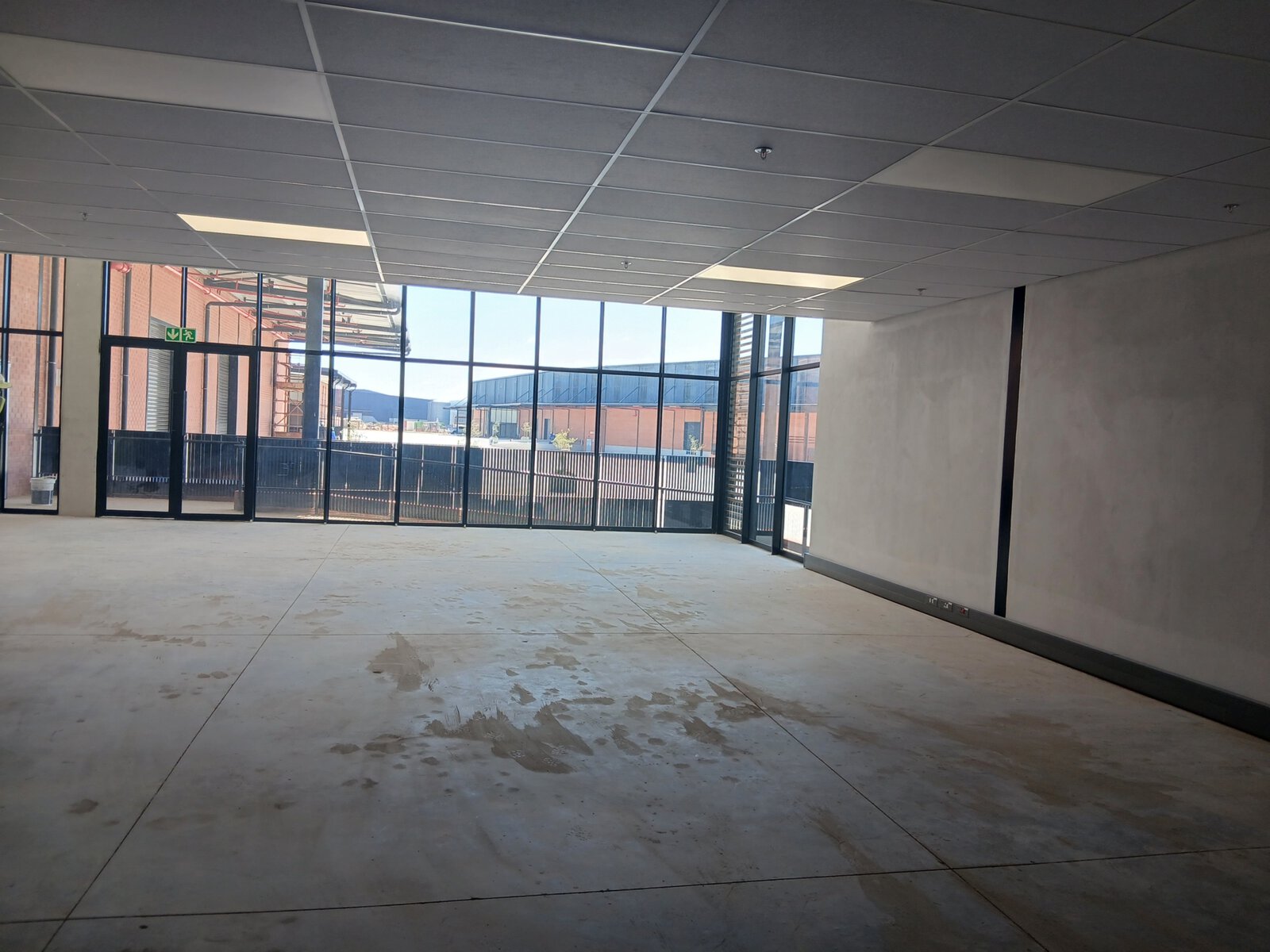 Spacious interior of Currie Group offices and warehouses with large glass windows and unfinished flooring, showcasing modern industrial design.