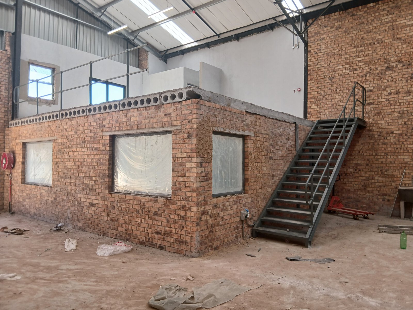 Construction of a modern office and warehouse with brick walls, metal stairs, and an industrial interior setting.