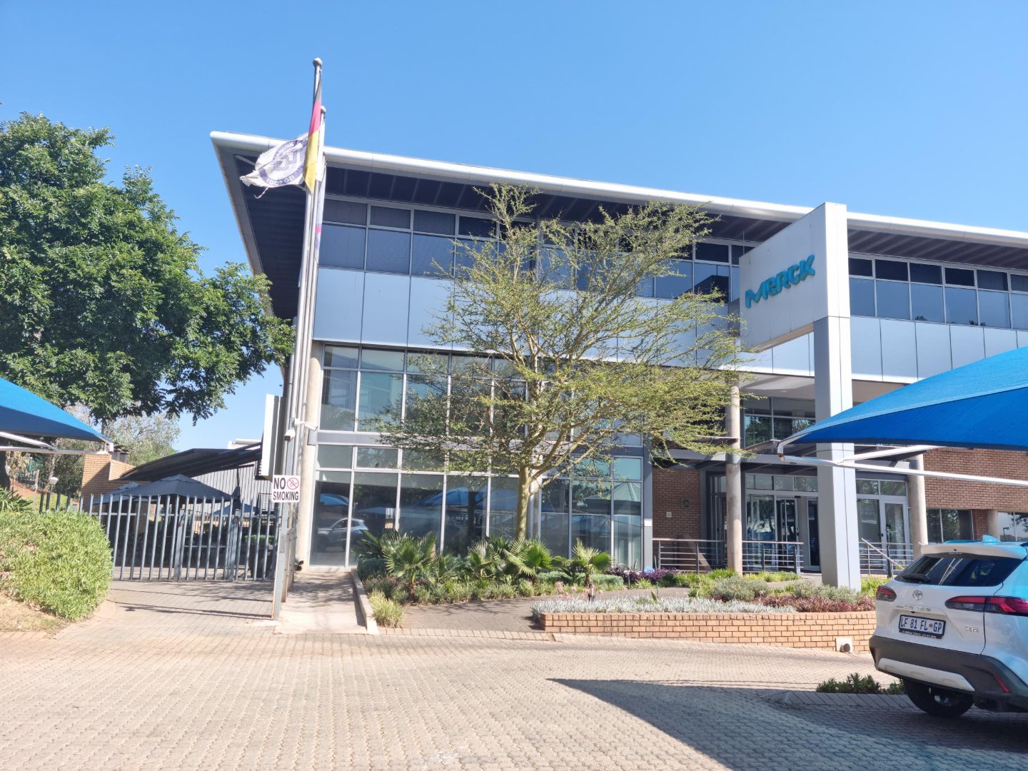 Modern office building of Currie Group with glass facade and surrounding greenery, under a clear blue sky.