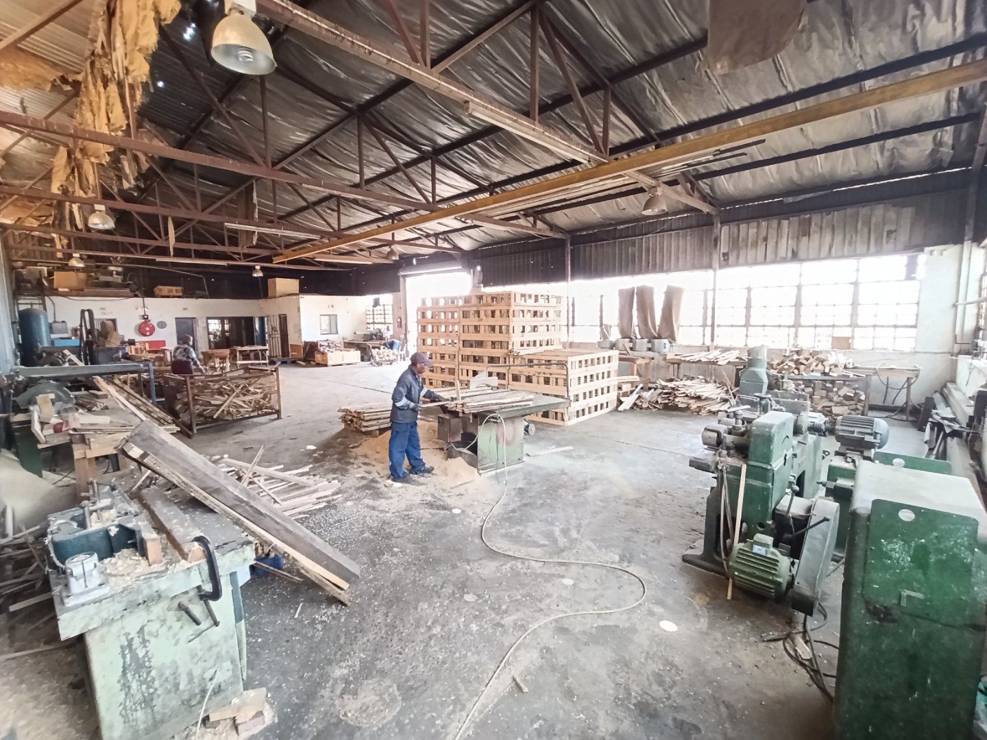 Spacious industrial warehouse with machinery, workbenches, and a worker inspecting equipment in Alrode.