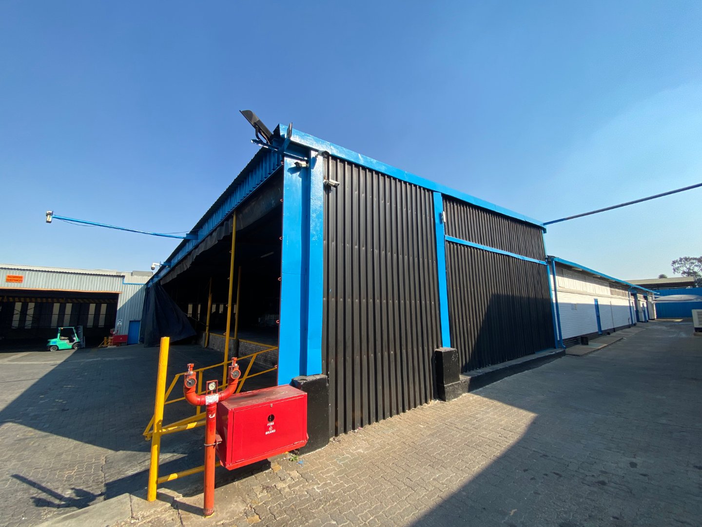 Large industrial warehouse with black and blue exterior in Alberton North, South Africa, under clear blue sky, suitable for industrial or commercial use.