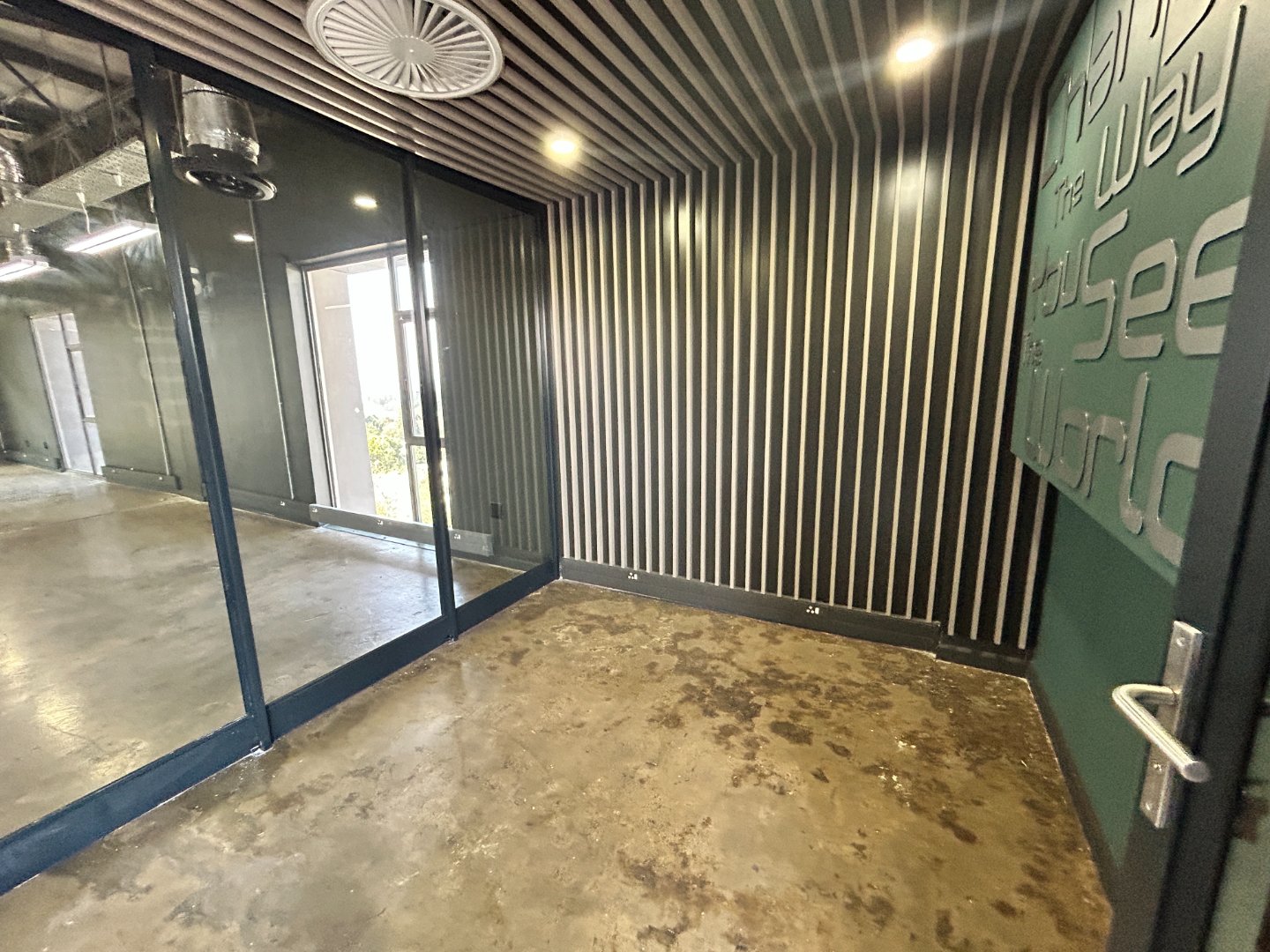 Contemporary office entrance with glass doors, striped wall design, and modern lighting, reflecting a professional workspace environment.