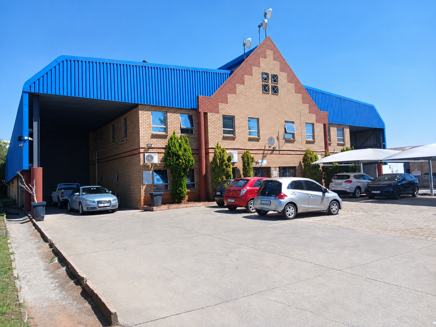 Modern office and warehouse building with parking lot and clear blue sky, part of Currie Group's facilities since 1887.